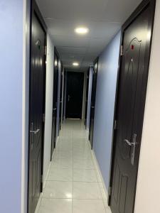 a hallway with black doors and a tile floor at Heavens Stay in Dubai