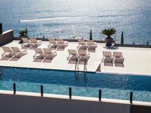 Una piscina con sillas y el océano al fondo. en Boutique hotel MaViE - Adults Only, en Neum