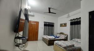 Una habitación con dos camas y un televisor de pantalla plana. en SHIV SHAKTI HOMESTAY, en Kevadia