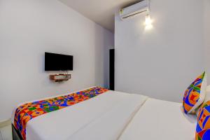 1 dormitorio con cama blanca y manta colorida en FabExpress Sky Inn en Pune