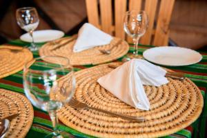 uma mesa com pratos de vime, guardanapos e copos de vinho em freedom inn em Arusha