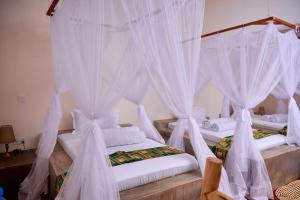 Cette chambre comprend 2 lits avec des rideaux blancs. dans l'établissement freedom inn, à Arusha