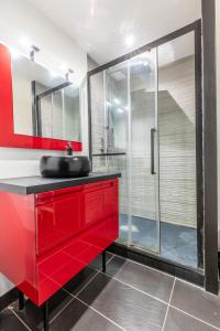 ein Badezimmer mit einem roten Waschbecken und einer Glasdusche in der Unterkunft F3 charmant neuf et équipé avec balcon "Wailly" in Clermont-Ferrand