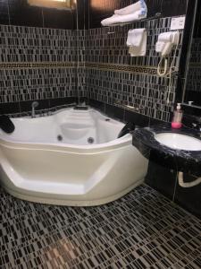 Emmad Furnished Hotel في أديس أبابا: حوض استحمام في حمام مع حوض