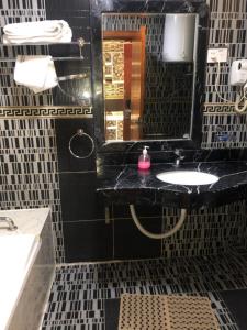 bagno nero con lavandino e specchio di Emmad Furnished Hotel ad Addis Abeba