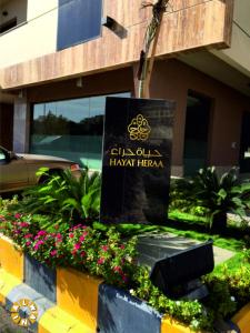 a sign in front of a building with flowers at Hayat Heraa Hotel in Jeddah