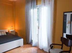 a bedroom with a bed and a window with white curtains at Beautiful house in Chalandri in Athens