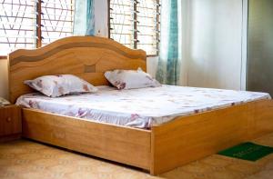 un letto in legno con due cuscini sopra in una camera da letto di J in G Retreat Center a Dawhwenya