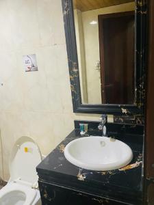 a bathroom with a sink and a toilet and a mirror at Desert Palm Aparthotel in Al Nairyah