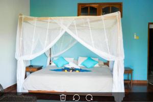 a bedroom with a white canopy bed with blue walls at Lovina Vibes Hotel in Balian
