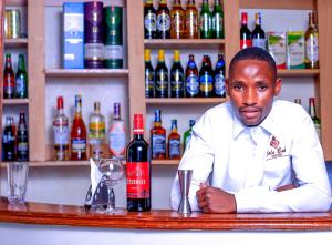 a man sitting at a bar with a bottle of wine at Calabash Hotel, Migori in Migori