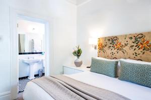 a white bedroom with a bed and a sink at Welgelegen House in Cape Town