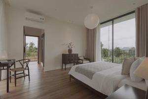 a white bedroom with a bed and a desk and a window at Nhãn Stay in Thôn Dương Xuân Hạ