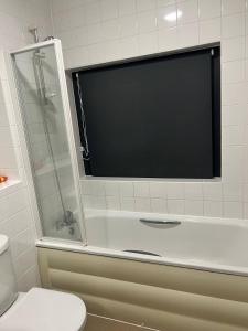 a bathroom with a toilet and a television on the wall at Central Town Apartment in Kent