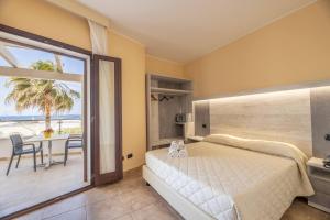 a bedroom with a bed and a balcony with a table at Hotel Salento Mirfran in Torre San Giovanni Ugento +152 photos