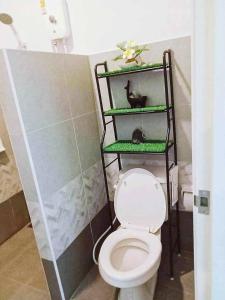 a bathroom with a toilet with a green shelf at บ้านคุณพระ แอท รพ.กรุงเทพ in Suratthani
