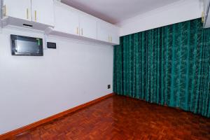 an empty room with a green curtain and a television at Enashipai Holiday Homes in Makandara