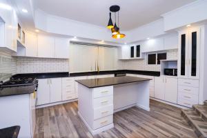 a kitchen with white cabinets and a black counter top at Enashipai Holiday Homes in Makandara
