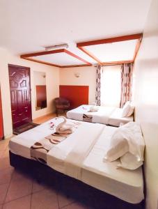 three beds in a room with a window at Calabash Hotel, Migori in Migori