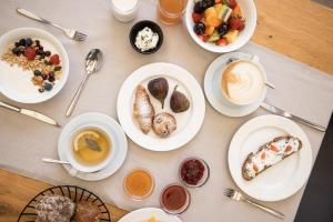 a table with plates of breakfast foods and cups of coffee at ALPIANA - green luxury Dolce Vita Hotel in Vollan