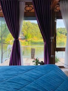 a bedroom with a blue bed and a view of a lake at Nha Ben Ho Venuestay in Hanoi