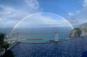 a rainbow over a balcony with a pool and the ocean at Hotel Klein Wien in Piano di Sorrento