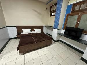 1 dormitorio con 1 cama y TV de pantalla plana en New Royal Hotel, en Nueva Delhi