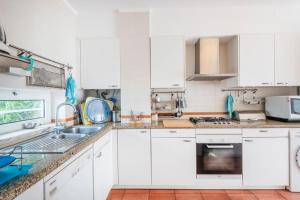 uma cozinha branca com armários e electrodomésticos brancos em Prainha Sunny 5BR Villa (up to 13 guests) em Alvor