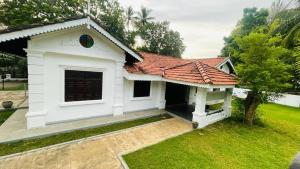 een klein wit huis met een rood dak bij Flamingo Village in Jaffna