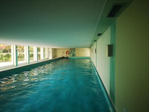 a swimming pool in a building with blue water at Ferienwohnung Kärnten Ossiacher See zwei Zimmer Appartement direkter Seezugang Strand beheizte Schwimmhalle in Bodensdorf