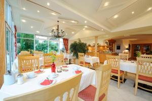a restaurant with white tables and chairs and windows at Hotel Sankt Leonhard - Dein Wohlfühlort zum Loslassen und Kraftschöpfen in Bad Birnbach