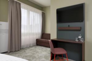 ein Hotelzimmer mit einem Bett, einem Schreibtisch und einem TV in der Unterkunft b-smart hotel Schönenwerd in Aarau