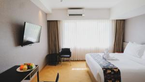 a hotel room with a bed and a table with a plate of fruit at Hotel Suni Sentani in Jayapura