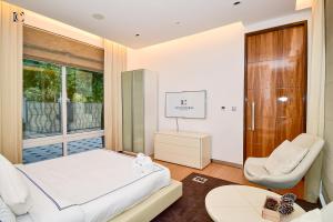 a bedroom with a bed and a chair and a window at Luxury 7BR Villa with Premium Amenities - Private Cinema, Pool and Gym -Emirates Hills in Dubai