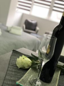 a bottle of wine and a rose next to a wine glass at Studio apartman Rose in Vinkovci