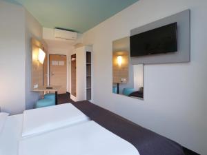 ein Hotelzimmer mit einem Bett und einem Flachbild-TV in der Unterkunft B&B Hotel Potsdam in Potsdam