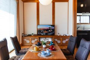 uma sala de jantar com uma mesa e uma televisão em 合い宿 くまもと em Kumamoto