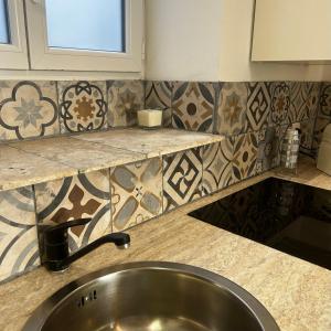 uma cozinha com um lavatório e um balcão com azulejos em Le ruisseau em Nice