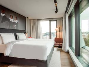 a bedroom with a large bed and a large window at Radisson RED Helsinki in Helsinki