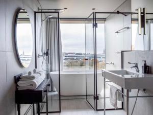 La salle de bains est pourvue d'une baignoire, d'un lavabo et d'une douche. dans l'établissement Radisson RED Helsinki, à Helsinki