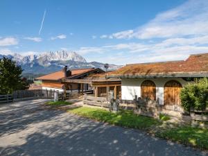 una casa con una valla y montañas en el fondo en Chalet Kitzalm, en Oberndorf in Tirol