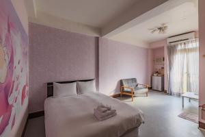 a bedroom with a large bed and a chair at Fengjia Love I Hostel in Taichung