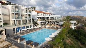 a hotel with a swimming pool with chairs and umbrellas at Panorama Village Hotel in Agia Pelagia