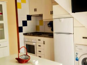 una cocina con nevera blanca y una cesta en una encimera en Apartamento Trafalgar con aire familias y parejas, en Conil de la Frontera