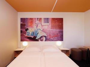 um quarto com uma cama e uma pintura de uma vespa em B&B Hotel Berlin-Süd Genshagen em Ludwigsfelde