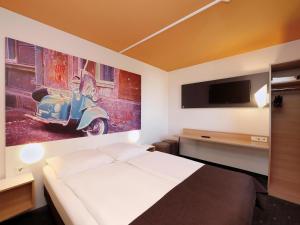 1 dormitorio con 1 cama y una pintura de un scooter en B&B Hotel Berlin-Süd Genshagen en Ludwigsfelde