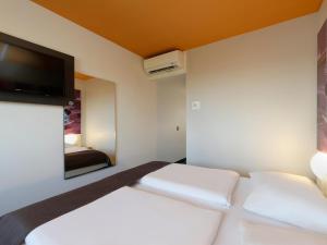 um quarto com 2 camas e uma televisão de ecrã plano em B&B Hotel Berlin-Süd Genshagen em Ludwigsfelde