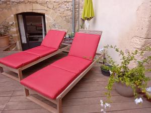 2 sillas acolchadas rojas sentadas en un patio en Le clos de l'Olivelle, en Gallargues-le-Montueux