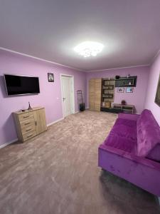 un soggiorno con divano viola e TV di Apartament Ingrid a Piatra Neamţ