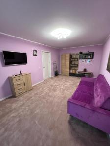 a living room with a purple couch and a tv at Apartament Ingrid in Piatra Neamţ